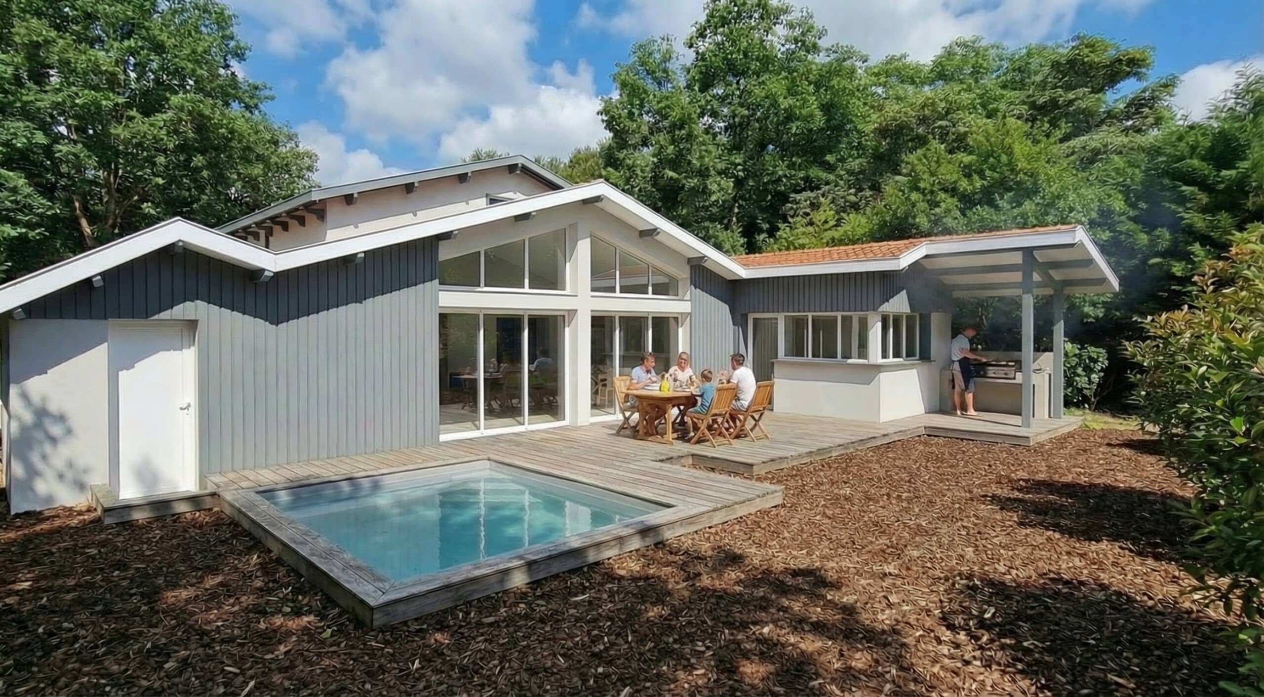 Maison moderne avec terrasse en bois, petite piscine et famille prenant un repas en extérieur dans un jardin arboré.
