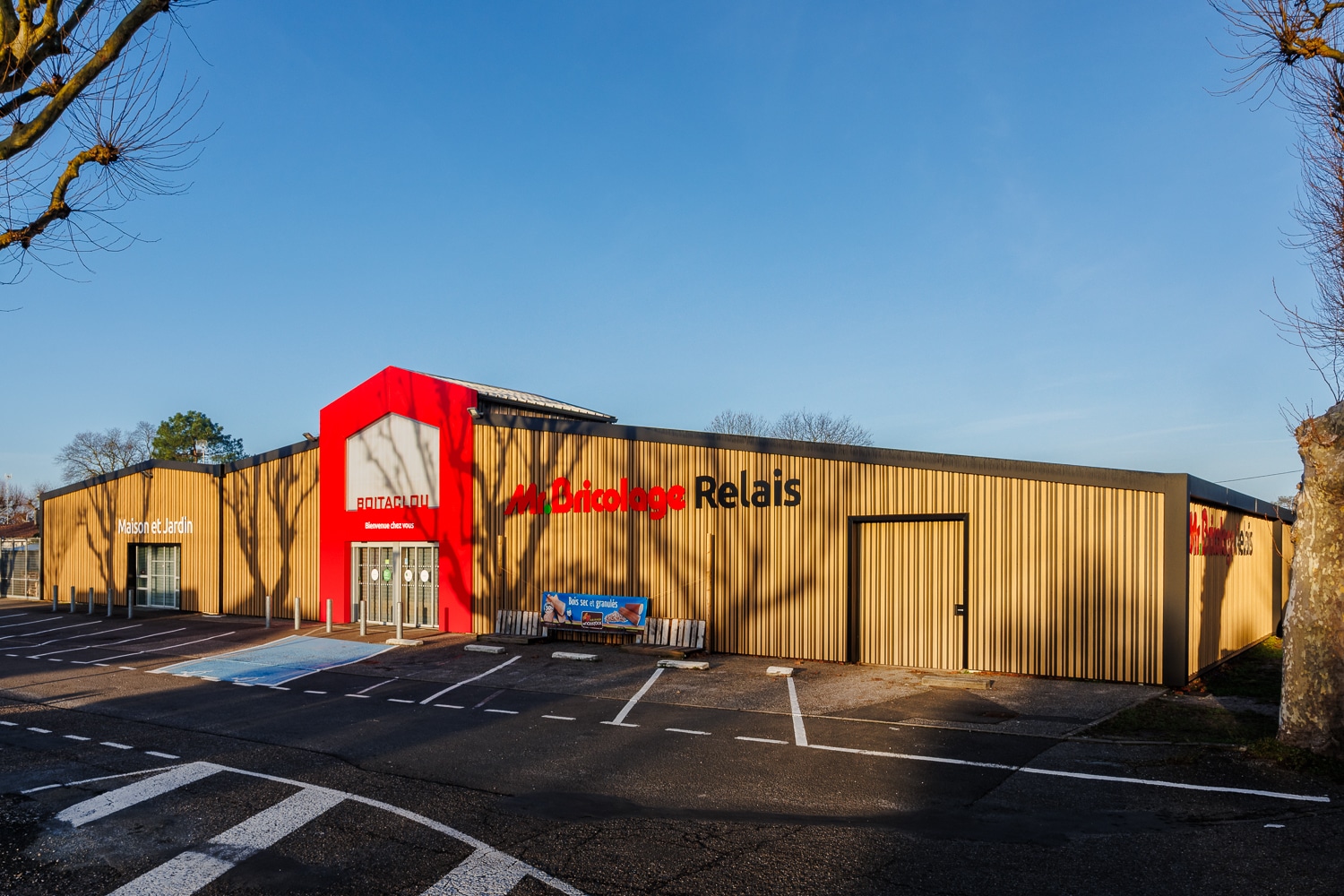 Magasin Mr. Bricolage Relais Boitaclou avec façade boisée et section Maison et Jardin sous un ciel bleu.