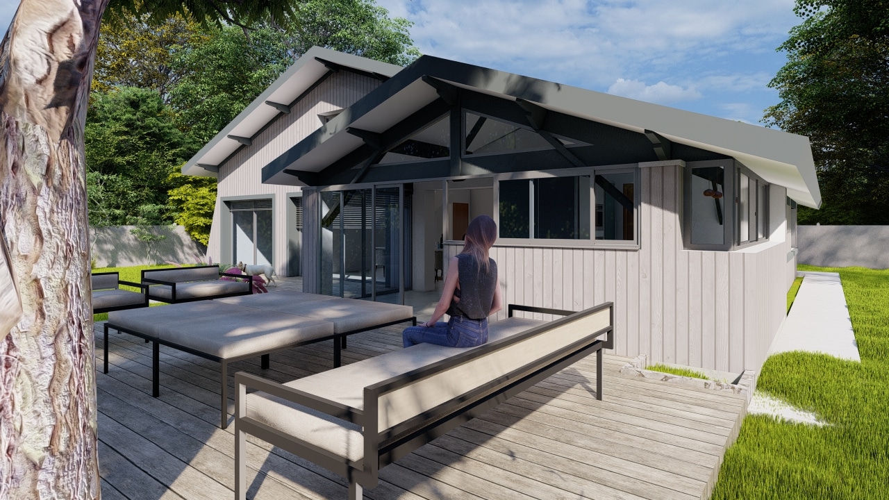 Maison moderne à bardage gris, terrasse en bois avec mobilier design et femme assise face à une grande baie vitrée.